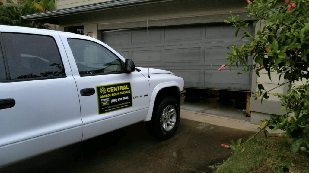 A Central Garage Door Service truck at a residence in Kapolei, HI, with a garage door that is off-track and needs repair.