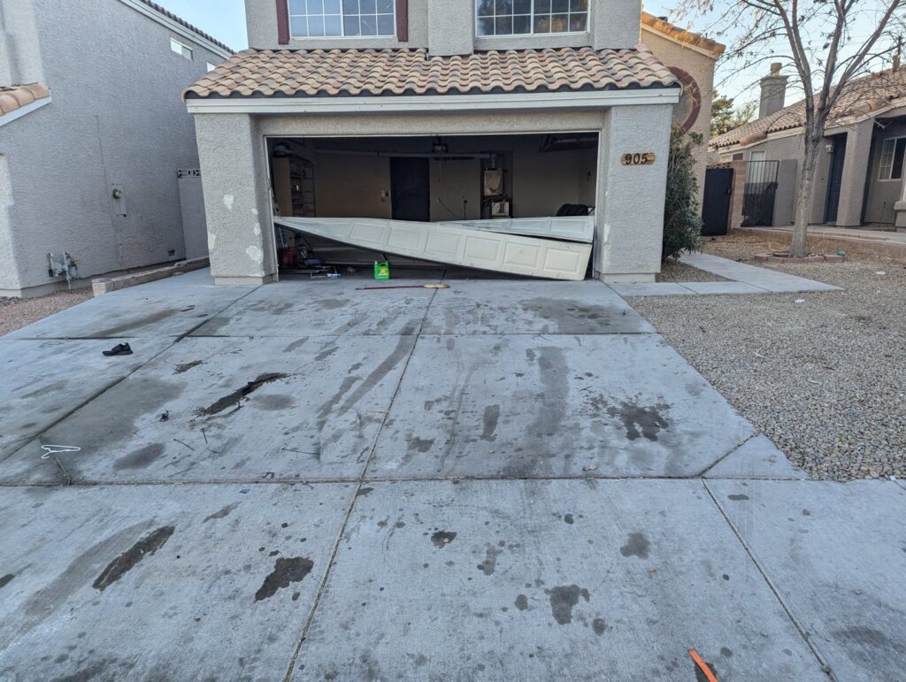 A severely damaged and collapsed garage door, needing repair or replacement service from Lifetime Garage Door in Las Vegas, NV.