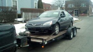 A damaged Honda Accord being towed on a trailer by Jr & Sr towing and recovery in Waukegan, IL.