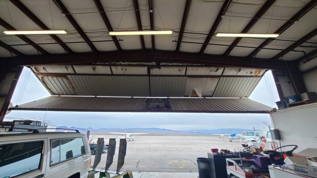 A damaged industrial hangar door requiring repair services from USA Doors in Doral, FL.