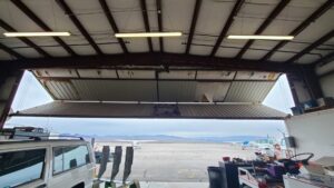 A damaged industrial hangar door requiring repair services from USA Doors in Doral, FL.