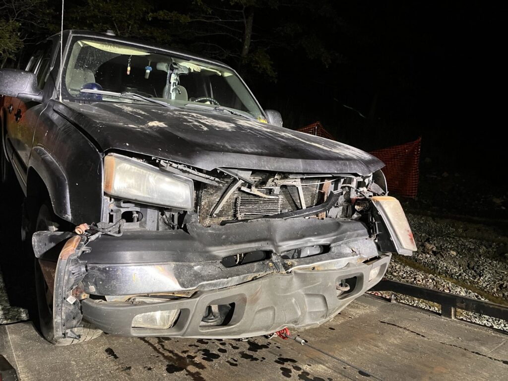 A damaged black pickup truck loaded onto a flatbed tow truck by TNF Towing in Montrose, PA.