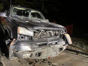 A damaged black pickup truck loaded onto a flatbed tow truck by TNF Towing in Montrose, PA.