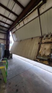 A damaged rolling garage door in need of repair, showcasing services by USA Doors in Doral, FL.