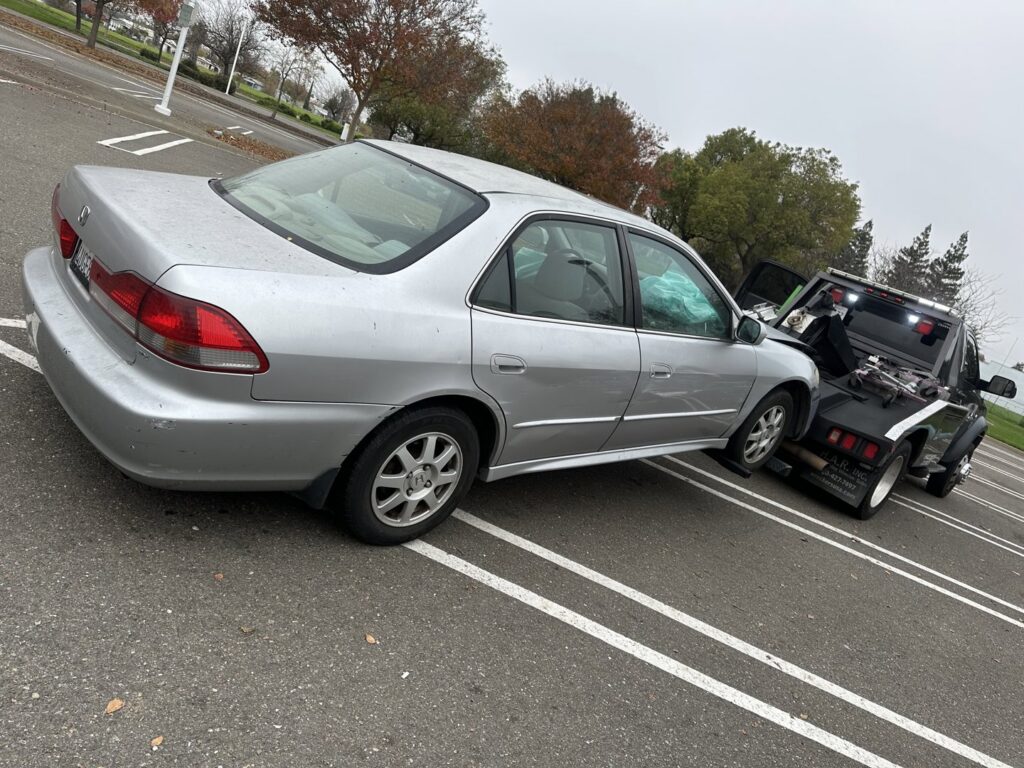 A damaged silver car being prepared for towing by R towing Services in Sacramento, CA.