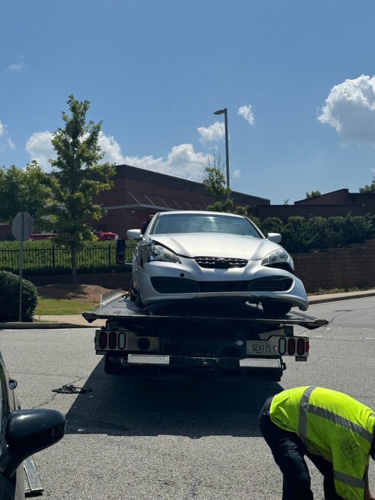 A damaged silver car being loaded onto a flatbed tow truck by Grace to Grace Towing in Atlanta, GA.