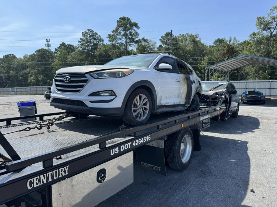 A damaged white SUV loaded onto a flatbed tow truck by Southeastern Towing and Transport in Savannah, GA.