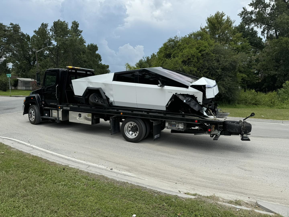 A damaged white Tesla Cybertruck being transported on a tow truck by Southeastern Towing and Transport in Savannah, GA.