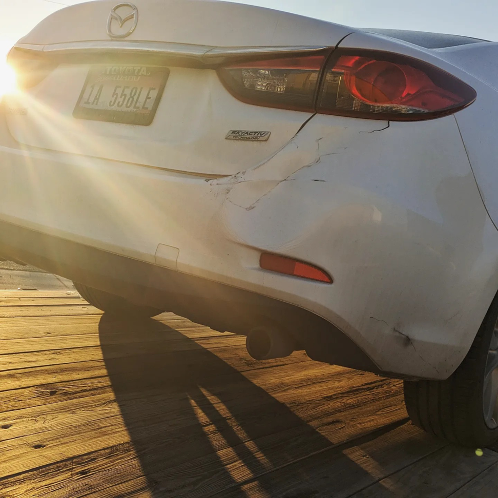 A damaged white car loaded onto a flatbed tow truck by Mountain Goat Rescue & Recovery LLC + Towing in Nampa, ID.