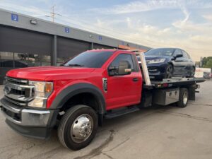 A dark blue sedan being transported on a flatbed tow truck by Quiñones Towing in Cleveland, OH.