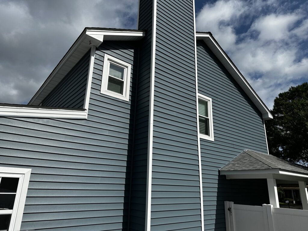 A residential property featuring dark blue siding and a matching chimney by Cordell Exteriors Inc in Chesapeake, VA