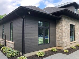 A modern home featuring dark gray horizontal siding combined with stone veneer by Ideal Siding Winston-Salem, NC.