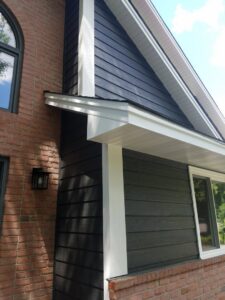 A close-up of a house exterior featuring dark gray horizontal siding with crisp white trim by Triton Exteriors in Maple Grove, MN.