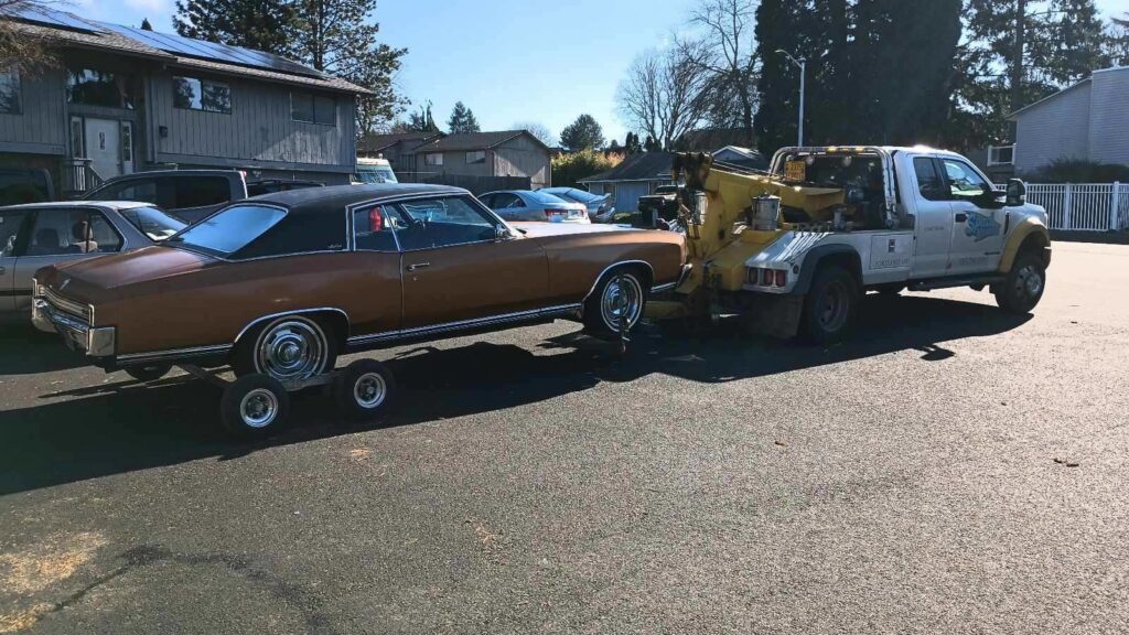 A dark green SUV being towed with dollies by Speed's Towing in Vancouver, WA.