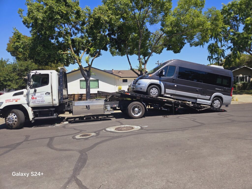 A dark grey camper van being towed on a flatbed tow truck by Ibanez Towing Service LLC in San Jose, CA.