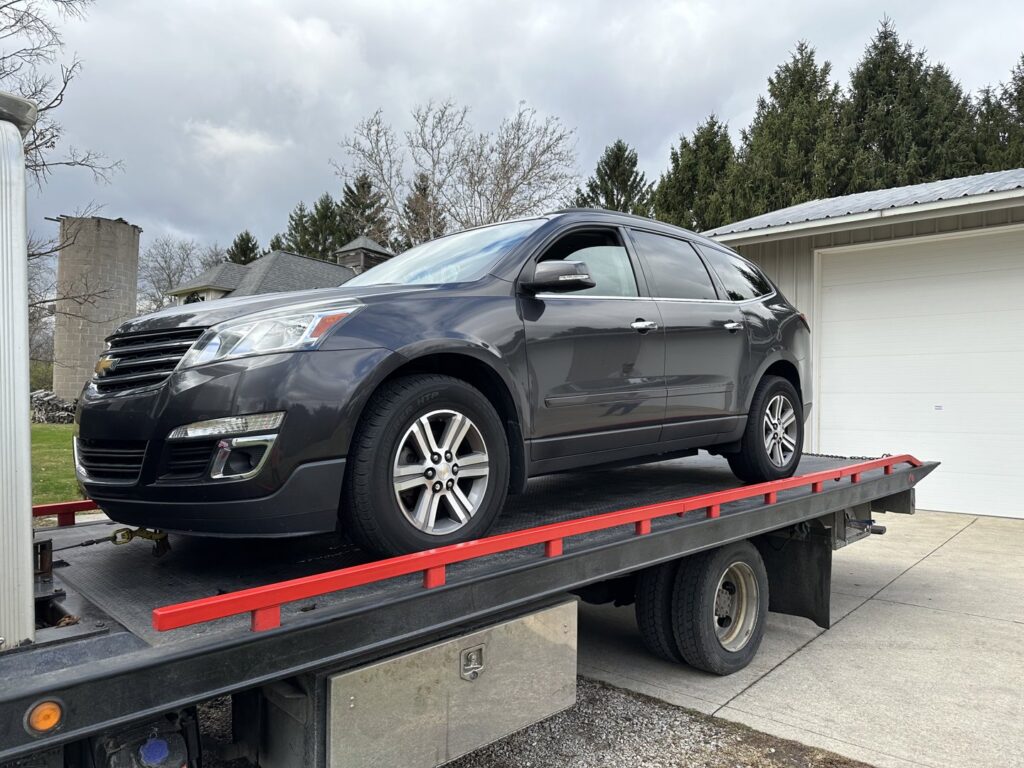 A dark grey SUV being transported on a flatbed tow truck by Anytime towing services in Columbus, OH.