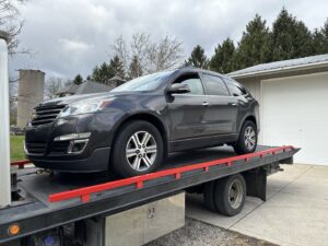A dark grey SUV being transported on a flatbed tow truck by Anytime towing services in Columbus, OH.