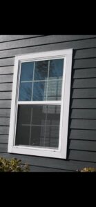 Close-up of dark horizontal siding with white window trim, showcasing quality work by Ideal Siding Austin in Austin, TX.