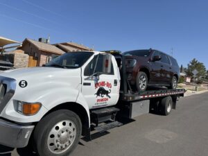 A dark red SUV being transported on a flatbed tow truck by Tow-Ro Towing in El Paso, TX.
