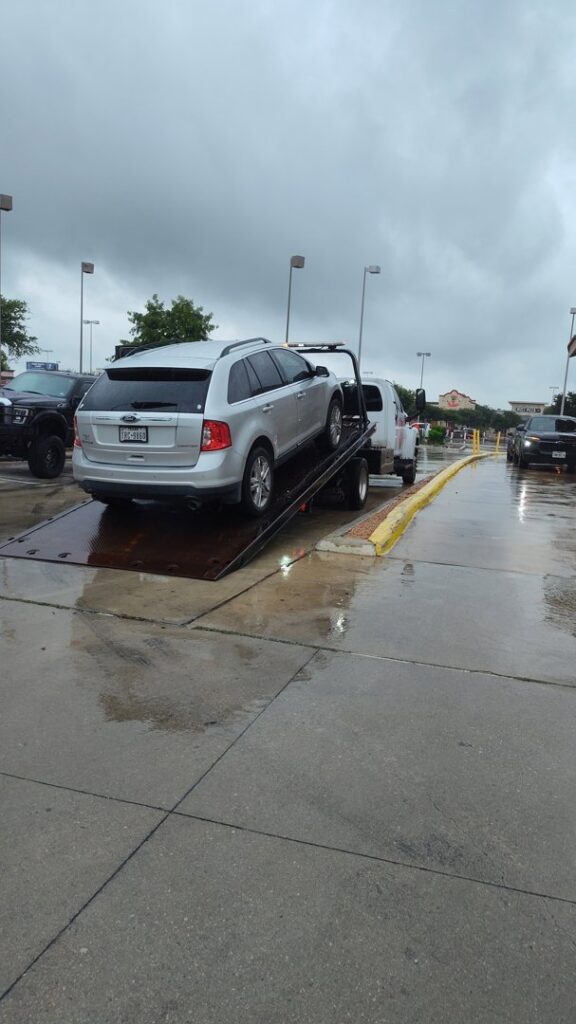 A dark grey SUV being transported on a flatbed tow truck by AB Towing & Transport in San Antonio, TX.