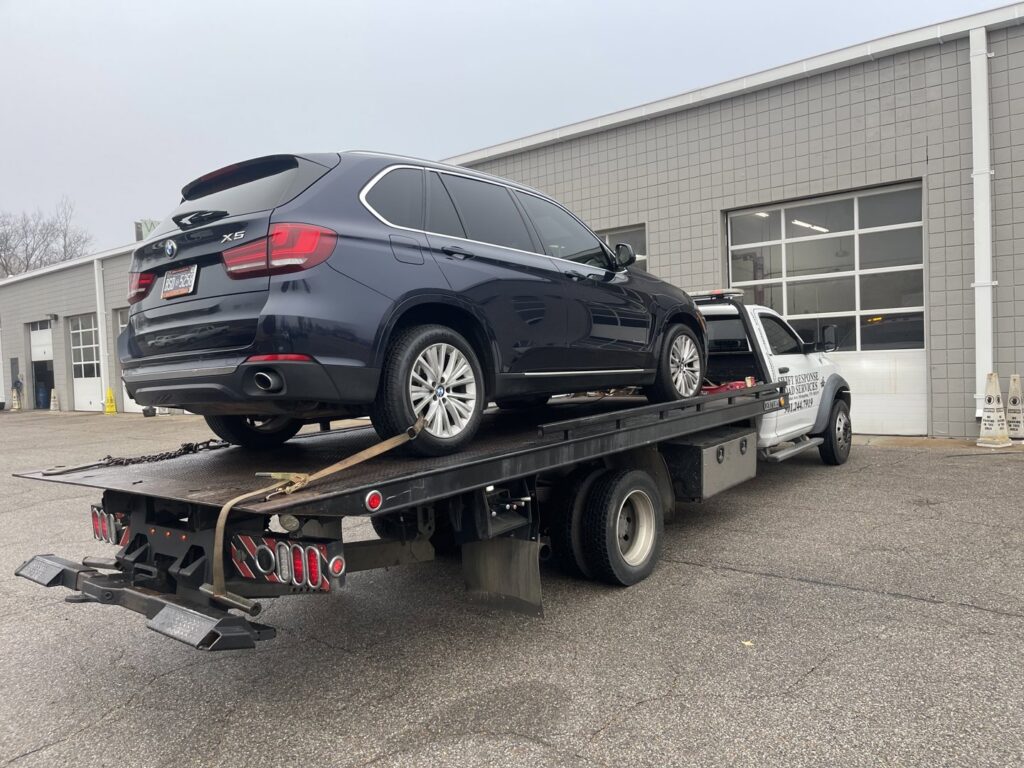 A dark SUV loaded onto a flatbed tow truck, providing towing services by Swift Response Road Services, LLC in Memphis, TN.