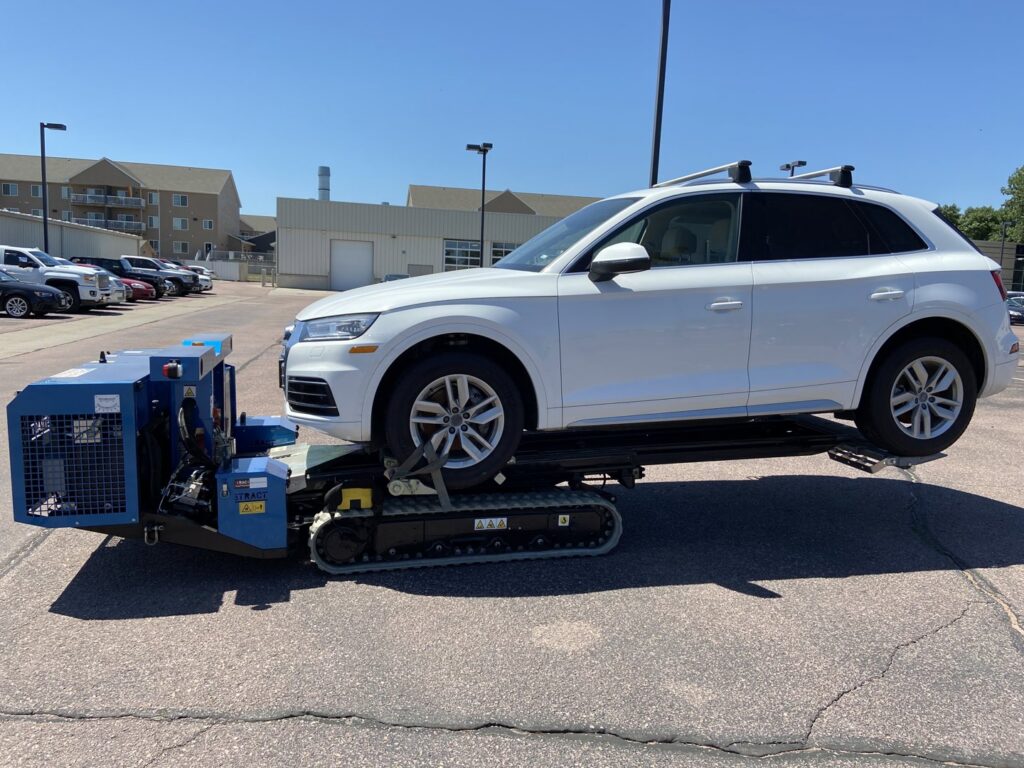 A dark SUV being towed up a driveway with specialized equipment by Jim & Ron's Service Inc. in Sioux Falls, SD.