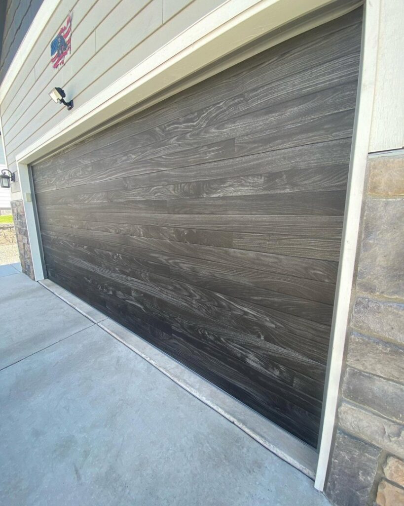 A dark wood-grain garage door installed on a residential house by Apex Garage Doors in Columbus, OH.