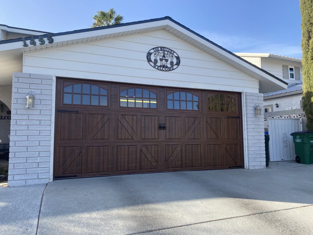 A dark wood-look garage door with decorative windows and hardware installed by Legacy ODS Garage Door Services in Las Vegas, NV.