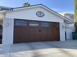 A dark wood-look garage door with decorative windows and hardware installed by Legacy ODS Garage Door Services in Las Vegas, NV.
