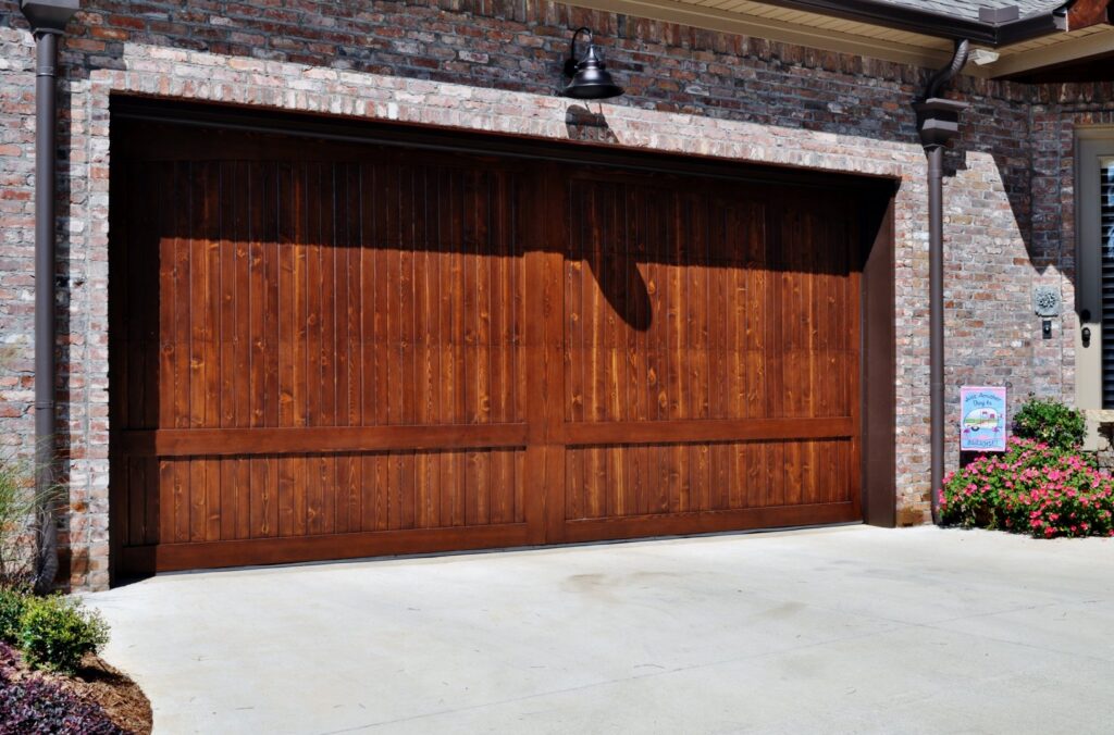 A stylish dark wood panel garage door installed on a brick home by Coney's Garage Doors in Conway, AR.