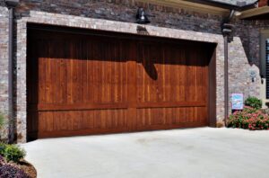 A stylish dark wood panel garage door installed on a brick home by Coney's Garage Doors in Conway, AR.