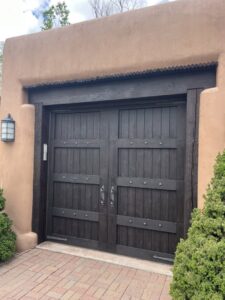 A dark wooden garage door with decorative studs and handles, installed by Mark's Garage Door Services in Santa Fe, NM.