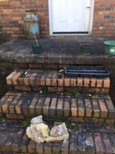Debris, rocks, and an old milk can being removed from brick steps by Athens Pressure Washing Services in Athens, GA.