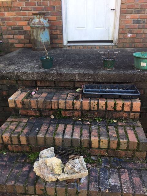 Debris, rocks, and an old milk can being removed from brick steps by Athens Pressure Washing Services in Athens, GA.