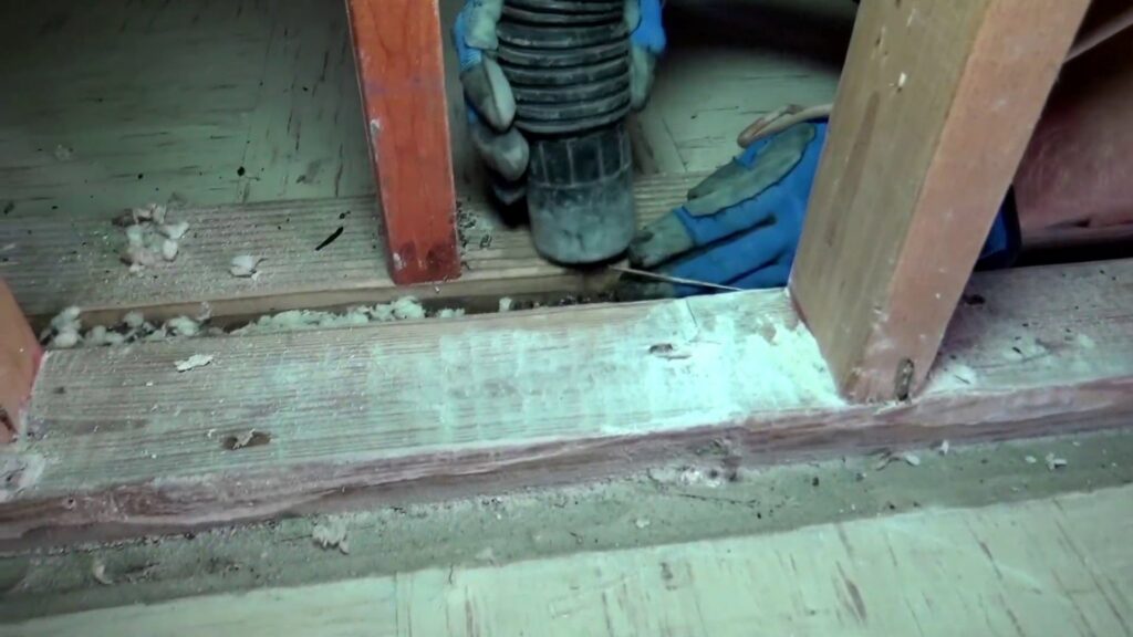 A SERVPRO of South Shreveport technician removing debris from between floor joists, a common task during water damage restoration in Shreveport, LA.