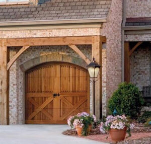A decorative wooden garage door on a brick residential home by Vertical Door Solutions in Sheridan, WY