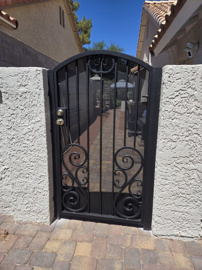 A decorative wrought iron pedestrian gate at an entry installed by Giddy Up Garage Doors & Iron in Las Vegas, NV.