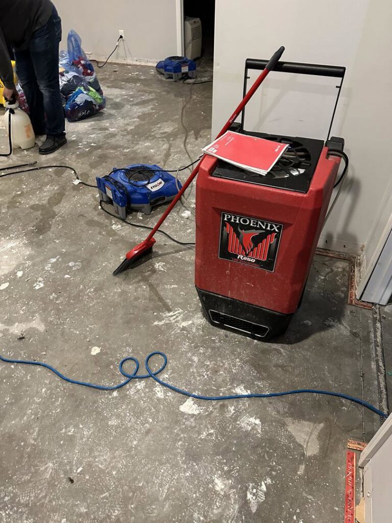 A Phoenix R250 dehumidifier and an air mover drying a room during water damage restoration by Restoration Alliance Services in Elk River, MN.