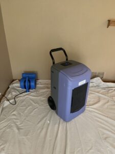 A dehumidifier and air mover on a drop cloth for water damage drying by Roeun's Restoration and Cleaning LLC in Rochester, MN.