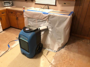 An industrial dehumidifier drying a plastic-sealed kitchen area during water damage restoration by One Stop Dry Out Restoration of Arkansas in North Little Rock, AR.