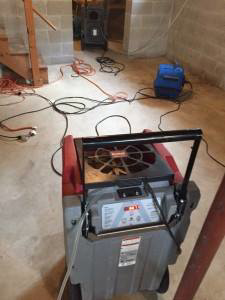 A professional dehumidifier and air movers working to dry out a water-damaged basement by Water Damage Squad in Philadelphia, PA.