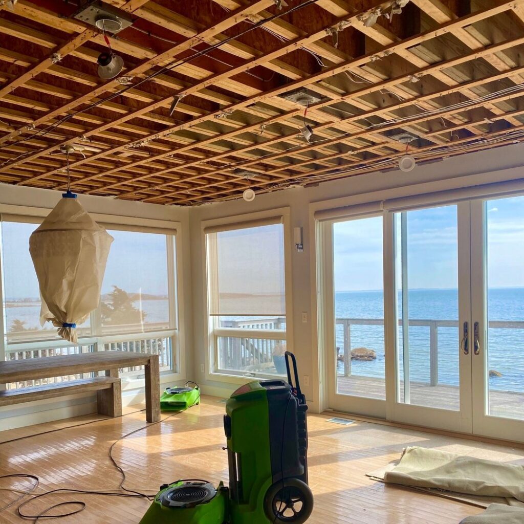 A dehumidifier operating in a room with exposed ceiling joists, indicating water damage restoration work by Servpro of Dartmouth / New Bedford in New Bedford, MA