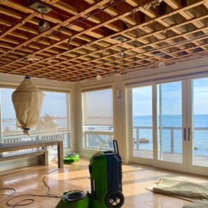 A dehumidifier operating in a room with exposed ceiling joists, indicating water damage restoration work by Servpro of Dartmouth / New Bedford in New Bedford, MA