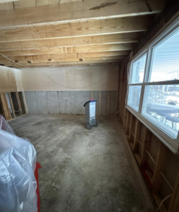 A large dehumidifier operating in a water-damaged basement with exposed studs by Ross Restoration in Fort Wayne, IN