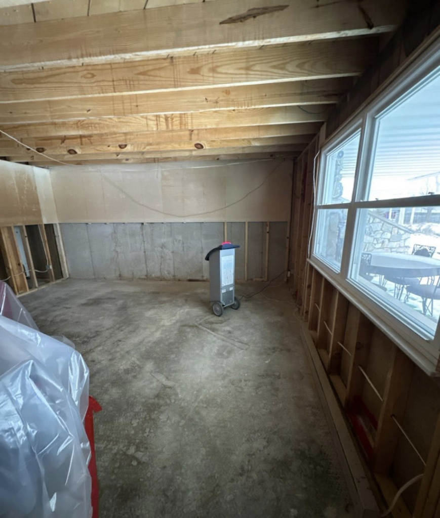 A large dehumidifier operating in a water-damaged basement with exposed studs by Ross Restoration in Fort Wayne, IN
