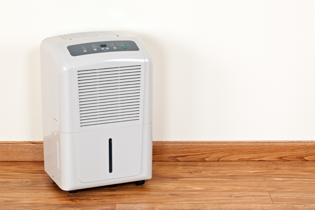 A modern dehumidifier operating in a room with hardwood floors, used for water damage restoration by Lowcountry Remediation in Charleston, SC.