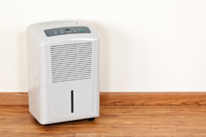 A modern dehumidifier operating in a room with hardwood floors, used for water damage restoration by Lowcountry Remediation in Charleston, SC.