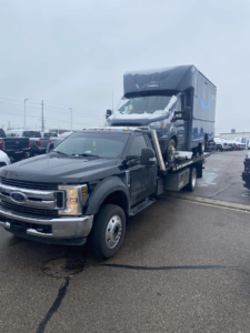 A delivery van transported on a flatbed tow truck by Triple T's Tow, Tire, & Transportation in Cincinnati, OH.