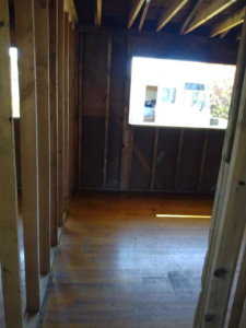 Demolished room interior with exposed wooden studs and a window view, demonstrating services by Building Assisting Group Demolition INC in Tacoma, WA.