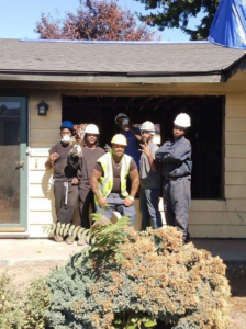 A demolition crew in hard hats standing in front of a gutted house, showcasing work by Building Assisting Group Demolition INC in Tacoma, WA.